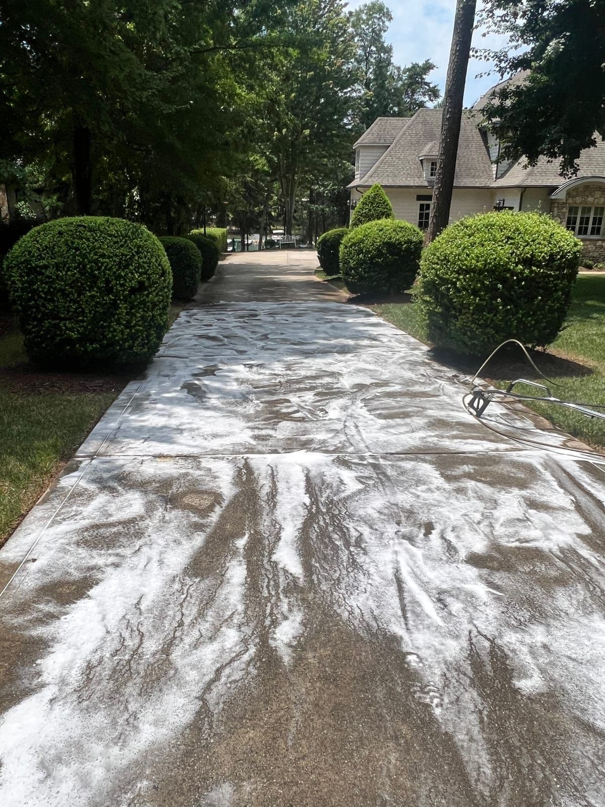Driveway concrete cleaning in progress with foam