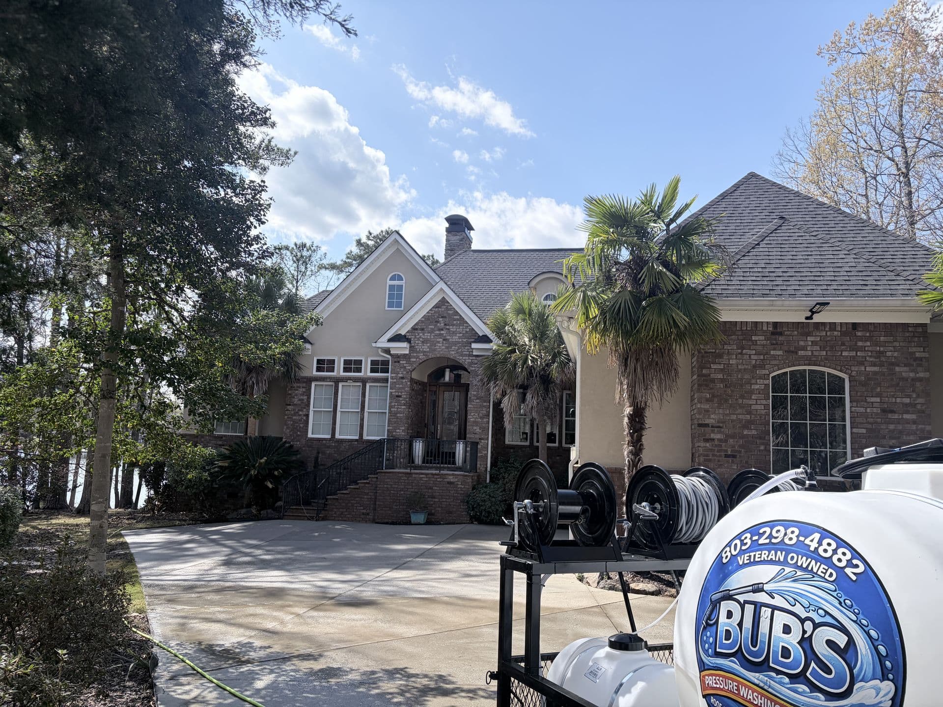 Bub's branded pressure washing tank and equipment in front of a stone home