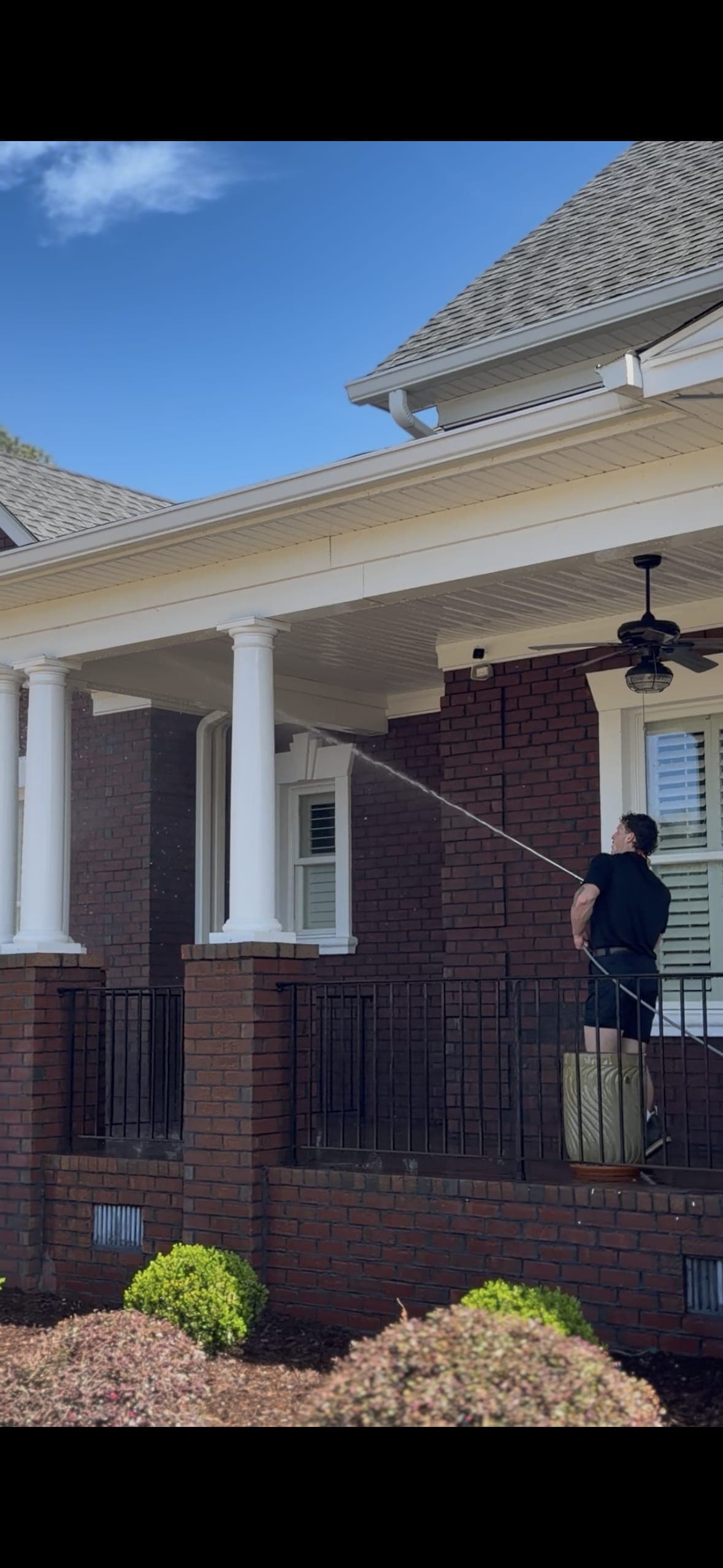 Technician spraying brick home exterior