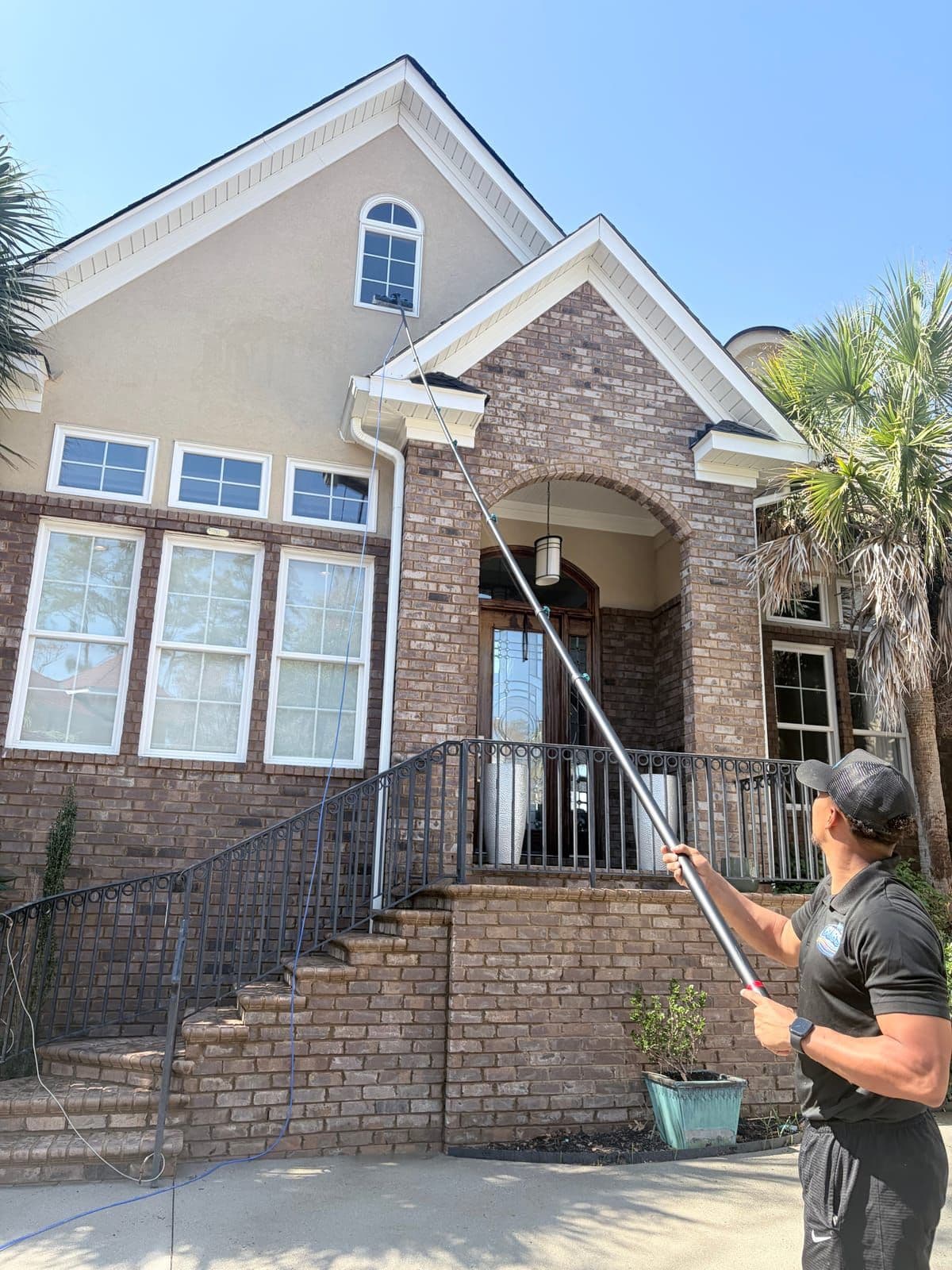 Technician pressure washing brick home exterior