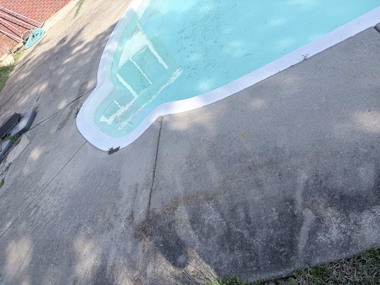 Pool deck edge showing algae-stained concrete beside cleaned concrete