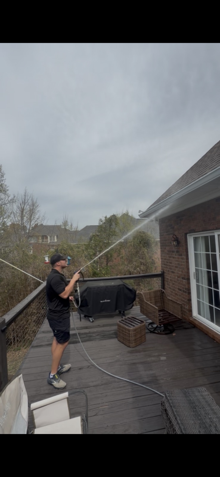 A Bub's technician soft washing a roofline at low pressure, reached from the ground
